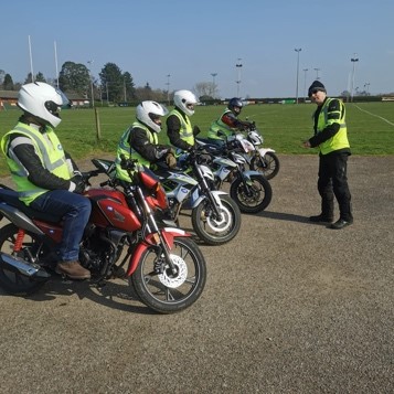 An instructor speaking with students on their bikes